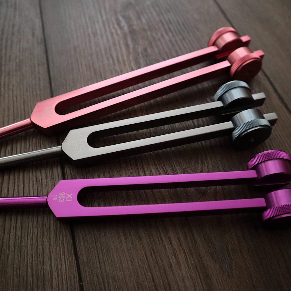 Three colorful tuning forks in pink, silver, and purple from Solfeggio Forks 9pc Set