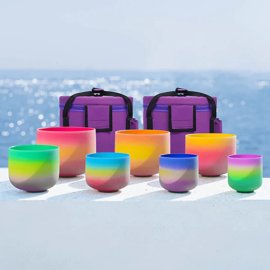 Colorful rainbow gradient crystal singing bowls with purple carrying cases for meditation