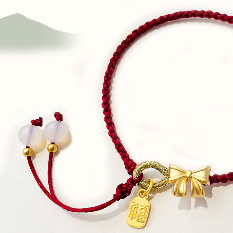 Bracelet en fil rouge avec breloque Fu et détail fleur de pêcher