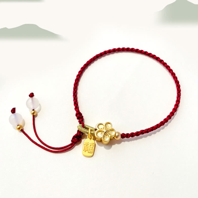 Bracelet en fil rouge avec breloque Fu et détail fleur de pêcher
