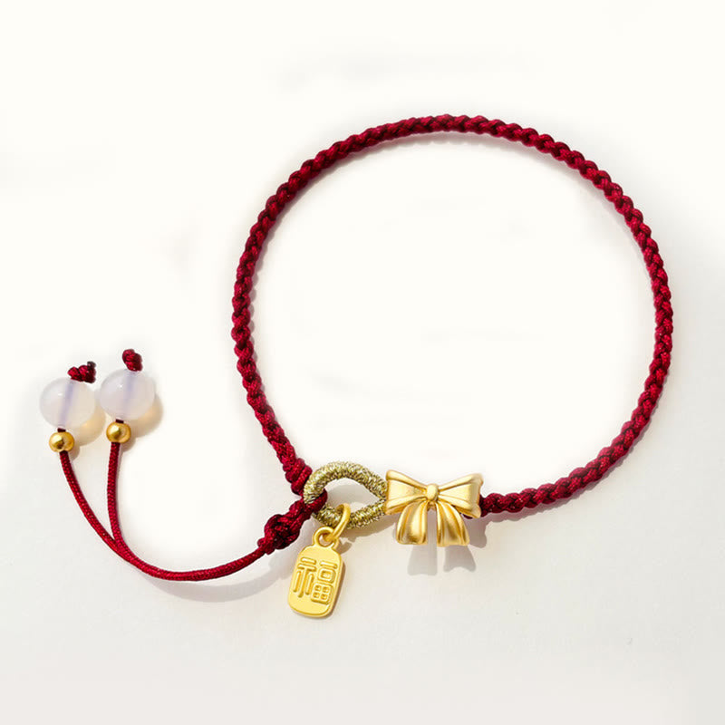 Bracelet en fil rouge avec breloque Fu et détail fleur de pêcher