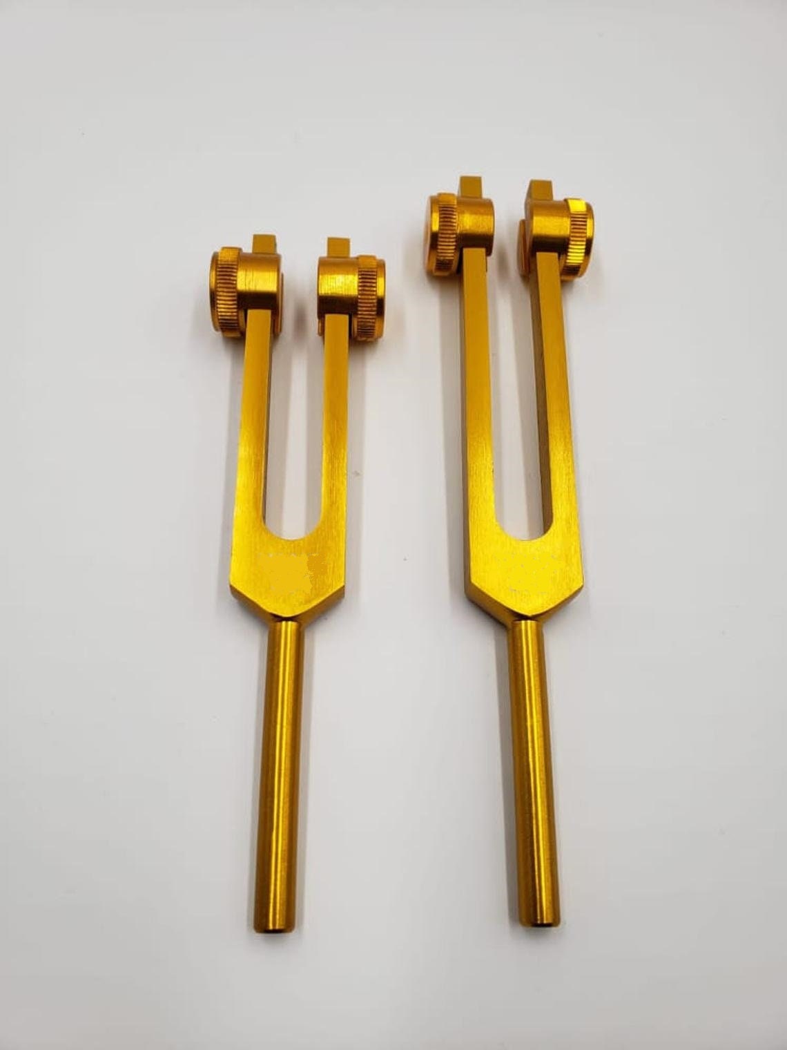 Two golden tuning forks from the Schumann Gold Tuning Fork Set side by side