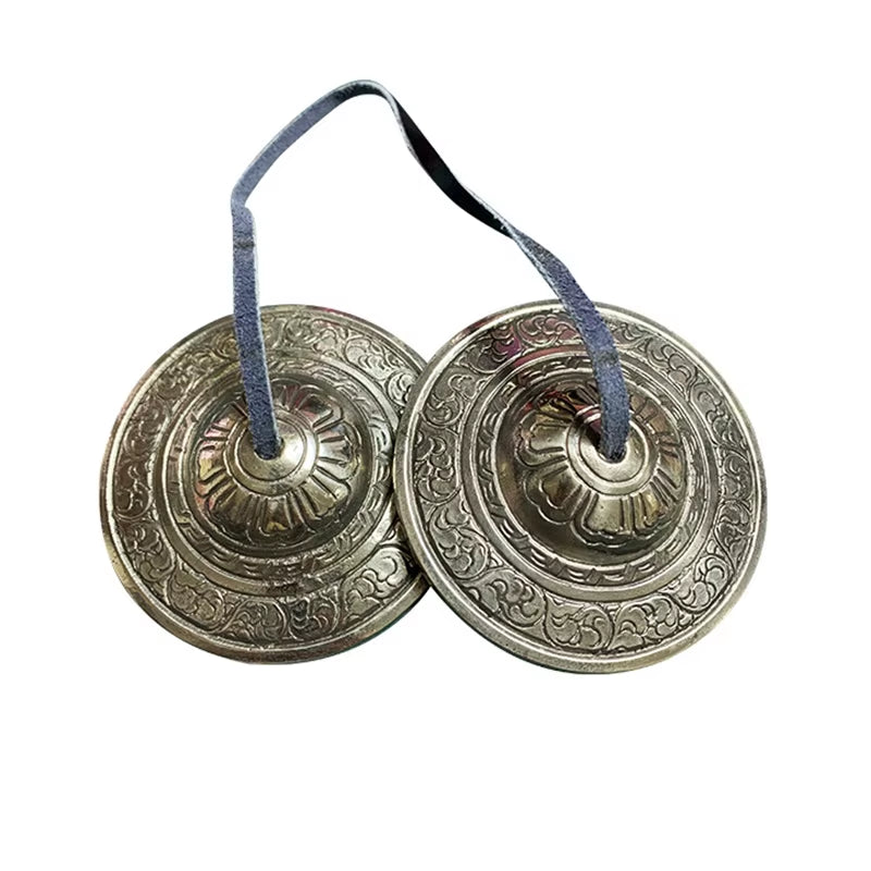 Pair of ornate metal Tibetan Tingsha cymbals connected by a blue ribbon for meditation