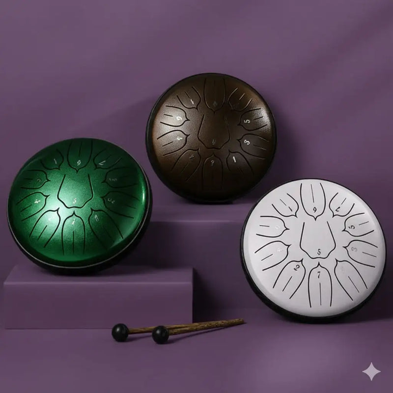 Three handcrafted steel tongue drums in vibrant green, matte bronze, and minimalist white finishes with engraved number markings.