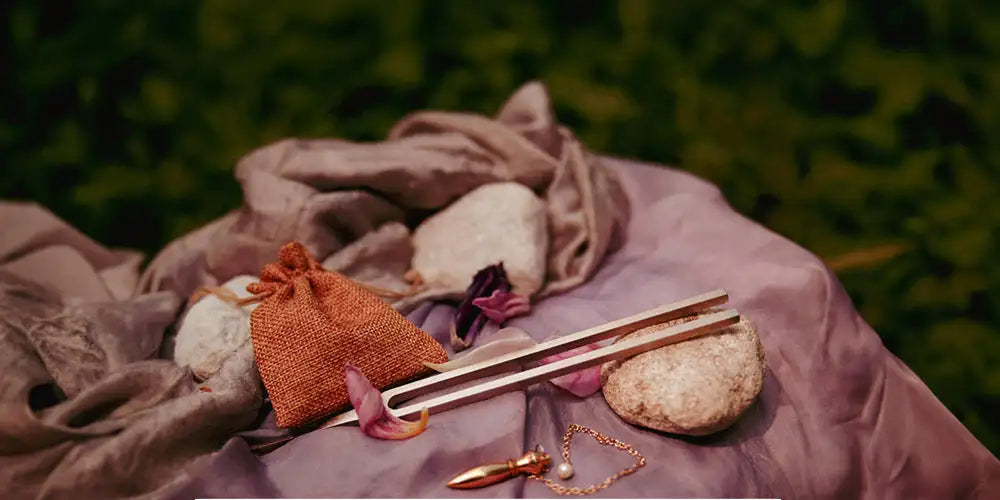 A sleek, metallic tuning fork with a polished silver finish rests on a soft purple fabric.