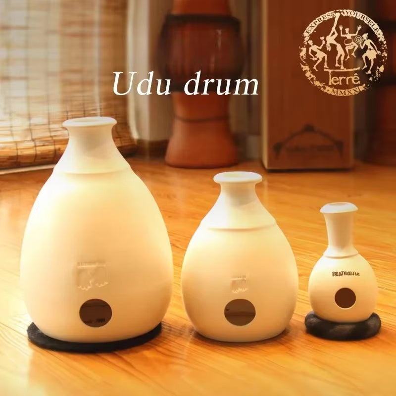 Three white ceramic Udu drums in varying sizes with circular sound holes